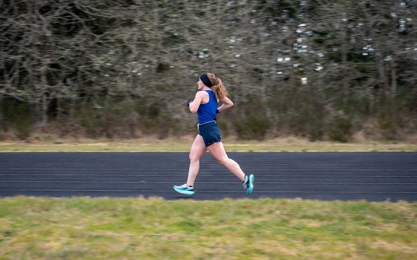 A woman wearing athletic gear jogs around a track.
