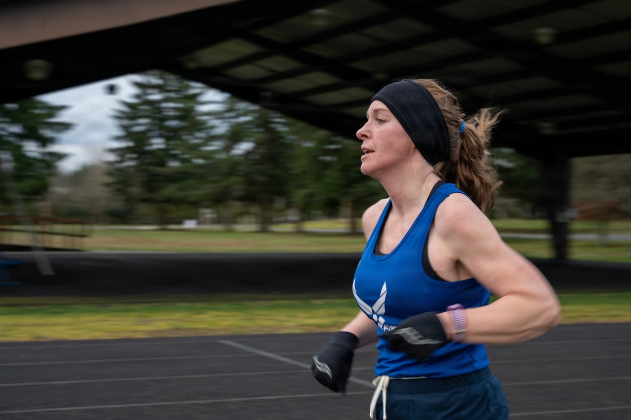 A woman wearing athletic gear jogs around a track.