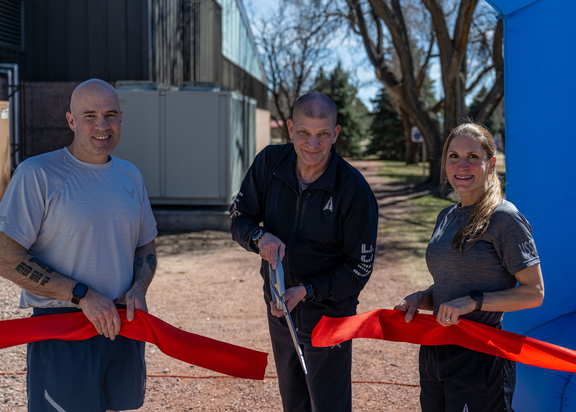 three servicemembers cut a ribbon.