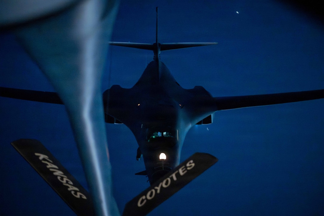 An aircraft’s boom extends to another aircraft while flying in a night sky.