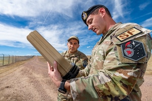 A Defender shows an EOD tech a drone buster.