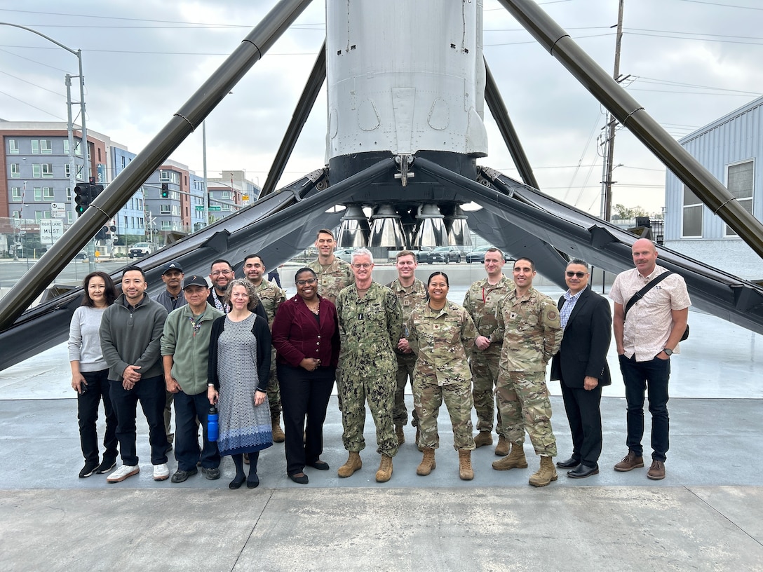 A group stands in front of a rocket booster static display