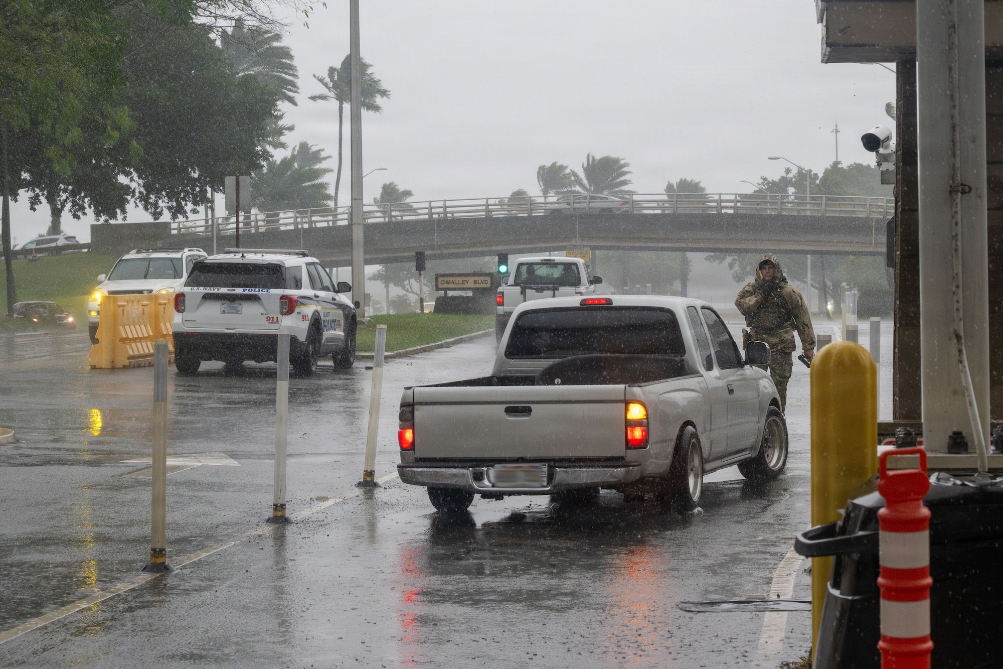 An Airman in rain gear directs a truck to move into a different lane.