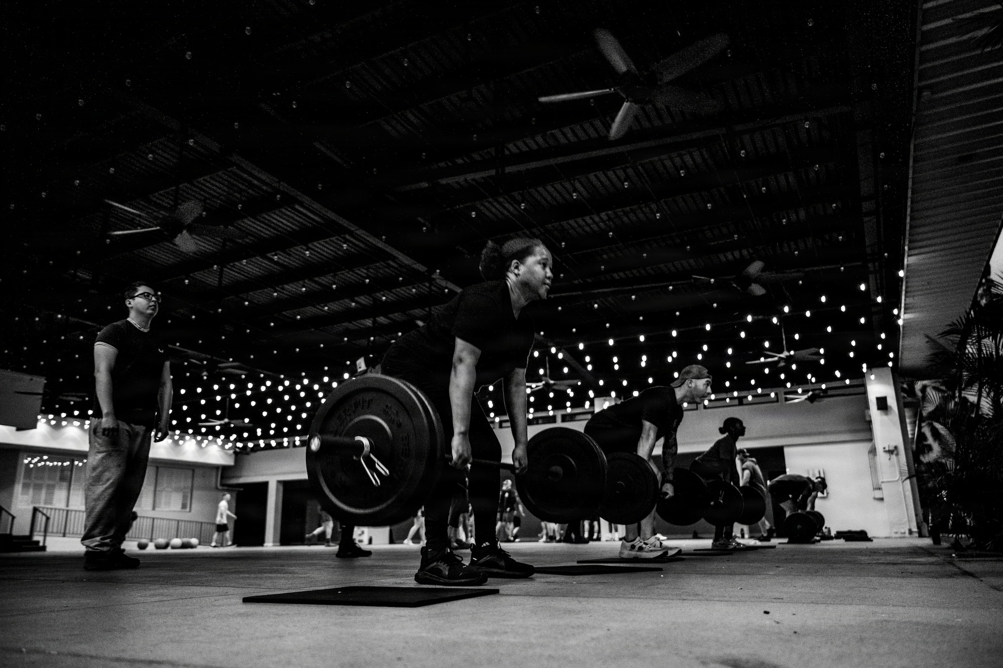 Multiple Airmen do deadlifts during a workout session.