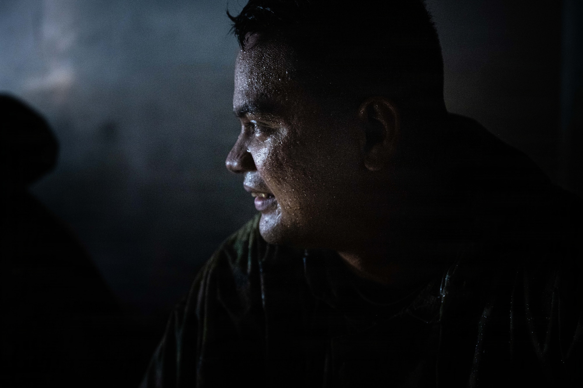An Airman sits inside a dark truck looking towards the light peeking through the driver's window.