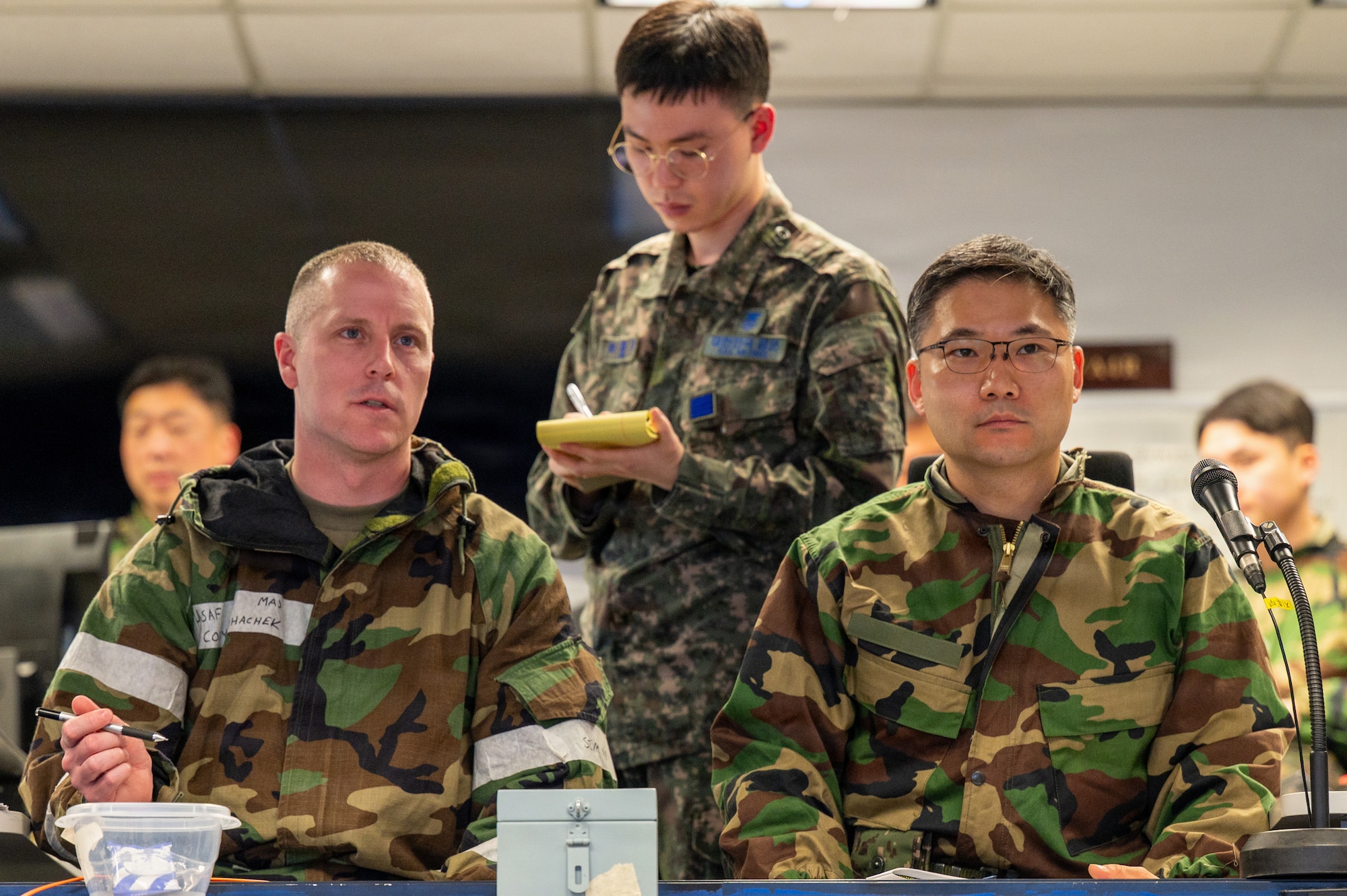 U.S. Air Force Maj. Cody Bohachek, left, Seventh Air Force logistics officer augmentee, and Republic of Korea air force Lt. Col. Cha Seungju, Combined Air Logistics Center chief of staff, listen to a shift change brief during exercise Freedom Shield 26 at Osan Air Base, Republic of Korea, March 12, 2026.