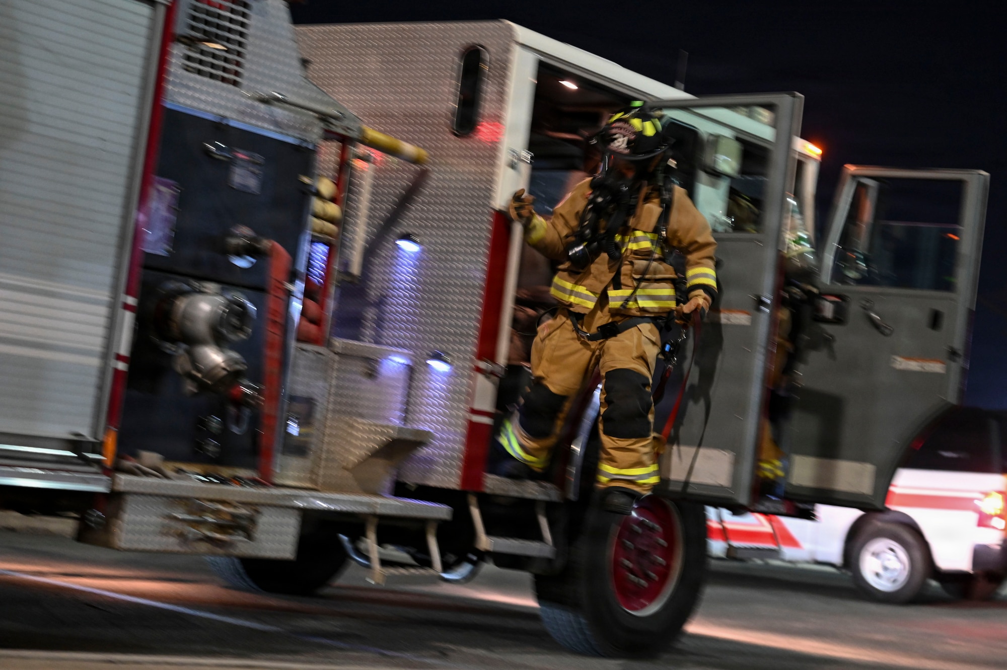 A Firefighter jumps from a firetruck.