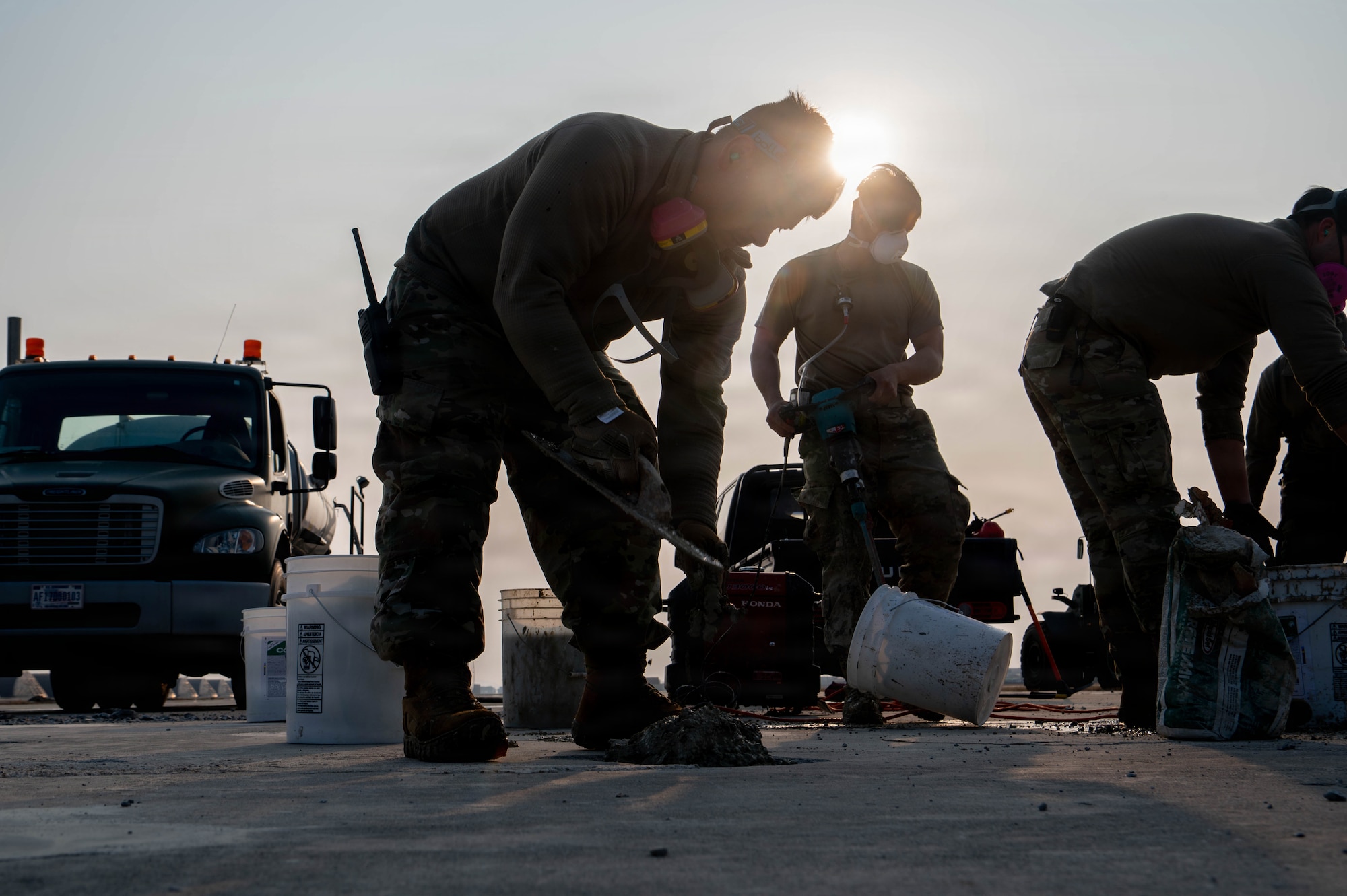 An Airman fills a pothole with concrete.