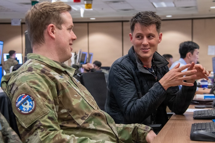 Ryan Bonacci, an exercise control group member attached to U.S. Space Forces - Korea, speaks to U.S. Space Force Maj. Dillon Hagerty, SPACEFOR-KOR director of force development, during exercise Freedom Shield 26 in the Pacific Air Simulation Center at Osan Air Base, Republic of Korea, March 10, 2026. Simulation-based training provided by the PASC allows exercise participants to receive near real-time feedback based on real-world scenarios and challenges. (U.S. Space Force photo by 1st Lt. Jimmy Nguyen)