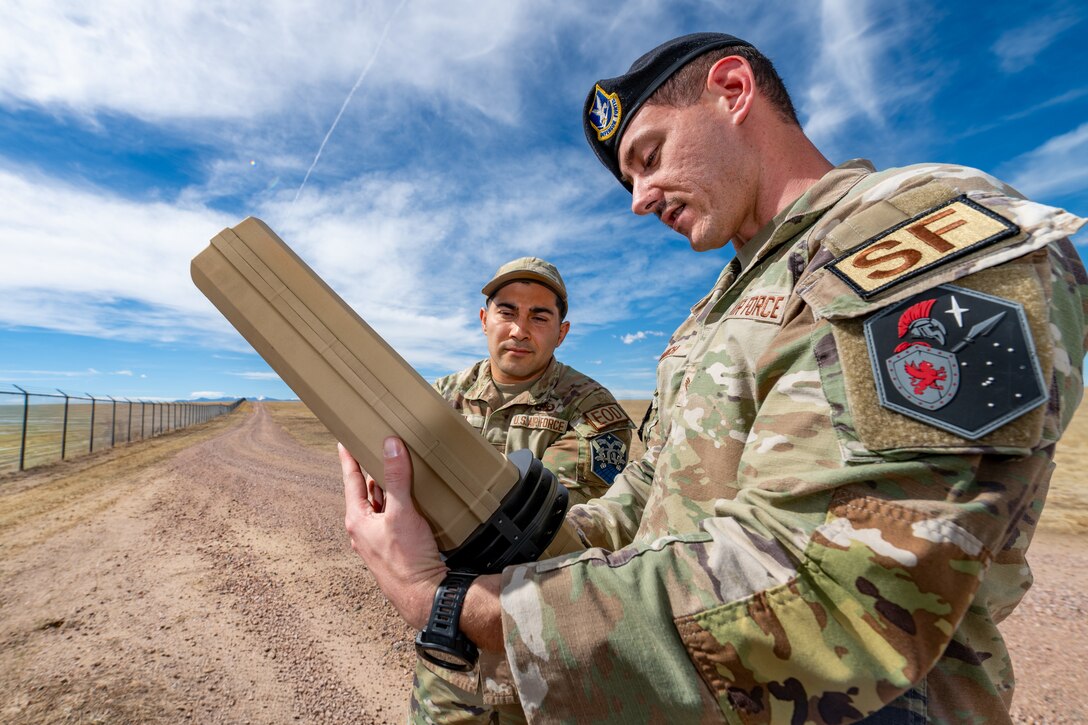 A Defender shows an EOD tech a drone buster.