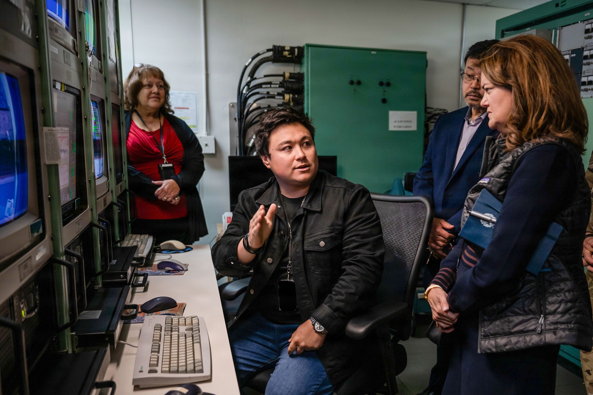 a person sits at a desk and explains readings on a screen to another person