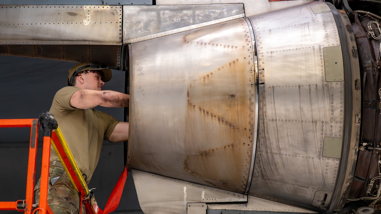 An Airman has his hands in an engine