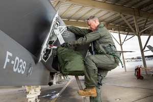 A photo of a green suited pilot climbing up stairs attached to a fighter aircraft
