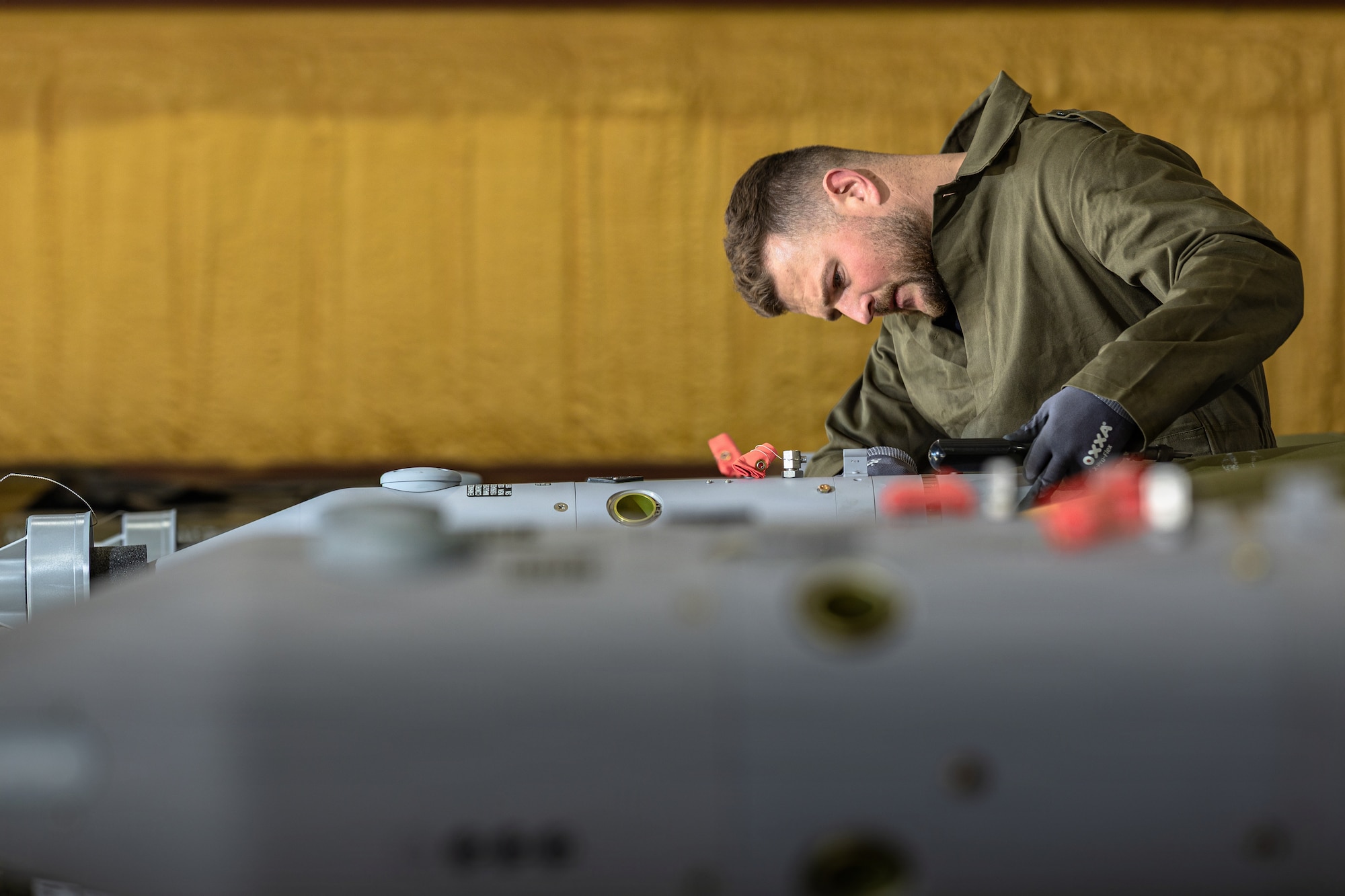 A photo of a weapons troop bent over closely examining munitions