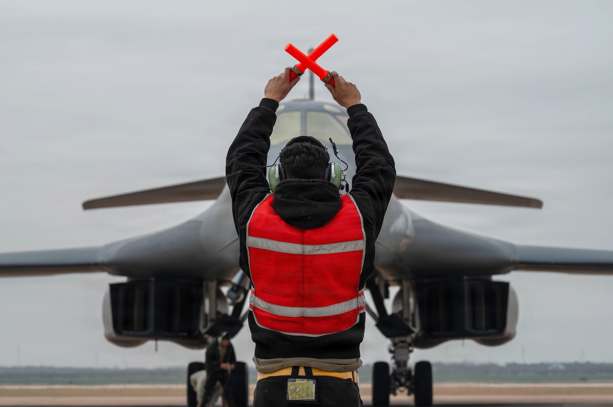 A crew chief marshals a B-1B Lancer after returning from a CONUS-to-CONUS mission supporting Operation Epic Fury, at an undisclosed location, March 4, 2026. The B-1B provided long-range strike capability, delivering precision munitions against designated targets in support of joint force operations. (U.S. Air Force photo)