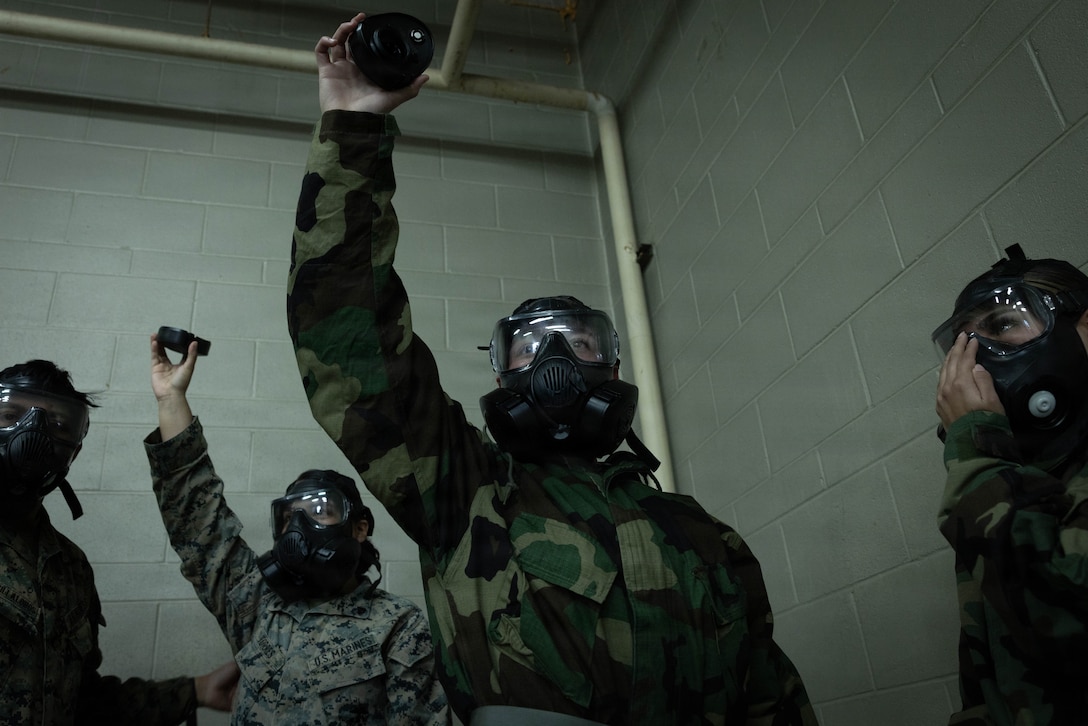 U.S. Marines and Sailors with 4th Medical Battalion, 4th Marine Logistics Group, Marine Forces Reserve, hold up a removed gas mask filter during a Reserve Mobilization Exercise, East Miramar, California, March 3, 2026. The week-long exercise validates the battalion’s ability to rapidly activate personnel and equipment, ensuring the unit can deliver ready forces in response to a national crisis. (U.S. Marine Corps photo by Lance Cpl. Claire Cheney)