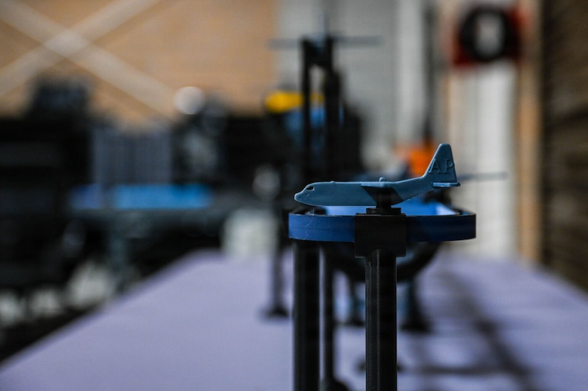 A small 3D printed model airplane is displayed on a stand.