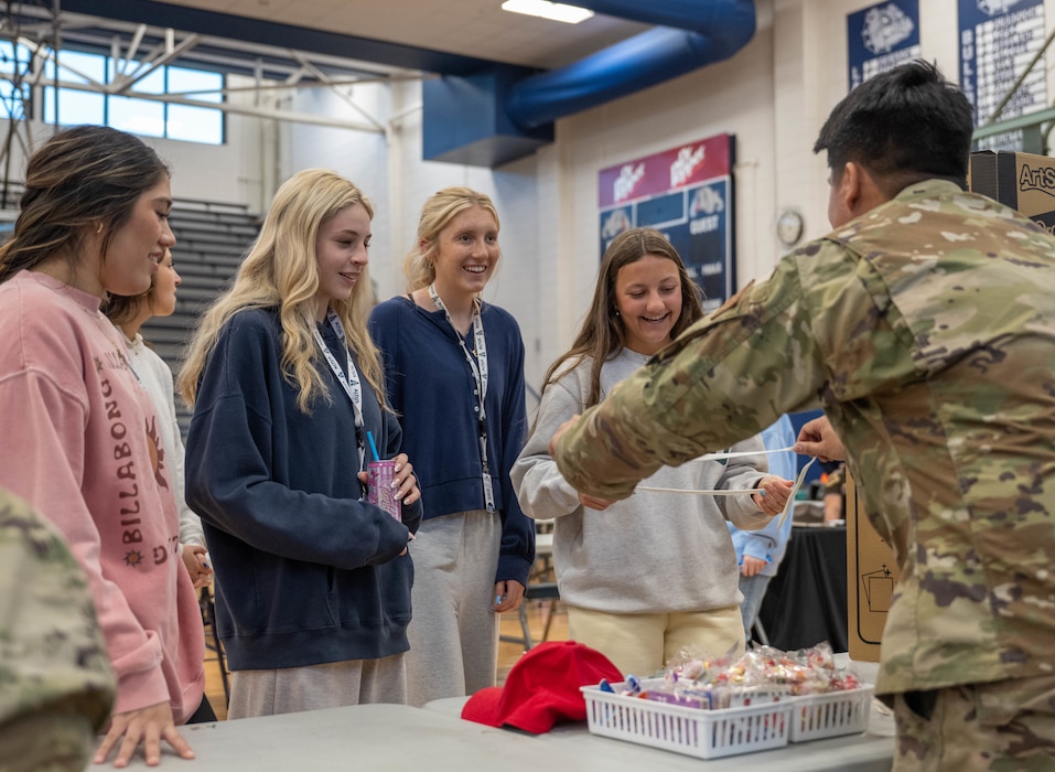 Altus High School students talk to a U.S. Air Force Airman at his booth during a career fair at Altus High School, Altus, Oklahoma, March 11, 2026. The career fair provided an opportunity for Airmen to make a positive impact on local students and to share with students some aspects of their duties. (U.S. Air Force photo by Airman 1st Class Emma Wright)