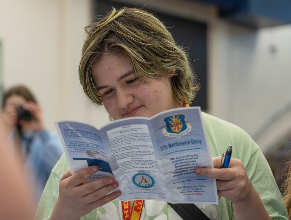 An Altus High School student reads a brochure about the 97th Maintenance Group during a career fair at Altus High School, Altus, Oklahoma, March 11, 2026. A civilian from the 97th Maintenance Group attended the career fair to help students learn more about the 97th Maintenance Group mission. (U.S. Air Force photo by Airman 1st Class Emma Wright)