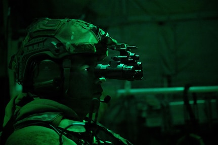 Airmen in combat gear sitting in dark