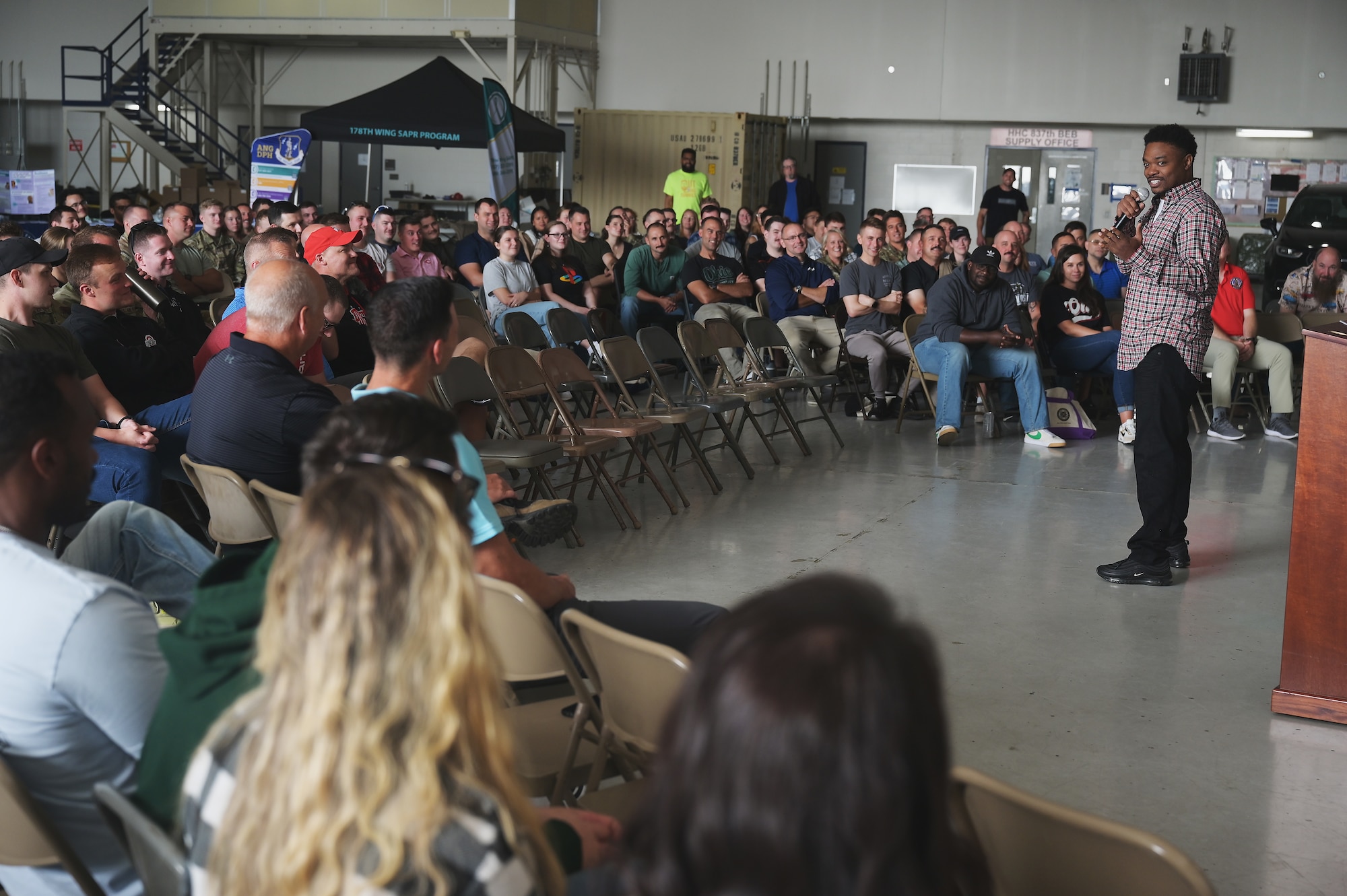 Neff Johnson, a comedian with One Degree of Separation, delivers jokes Sept. 17, 2025 to an audience of airmen of the 178th Wing  at the Springfield Air National Guard Base in Springfield, Ohio. Johnson was one of four comedians from One Degree of Separation who visited the wing to talk to the airmen about mental health and suicide prevention. (U.S. Air Force photo by Shane Hughes)