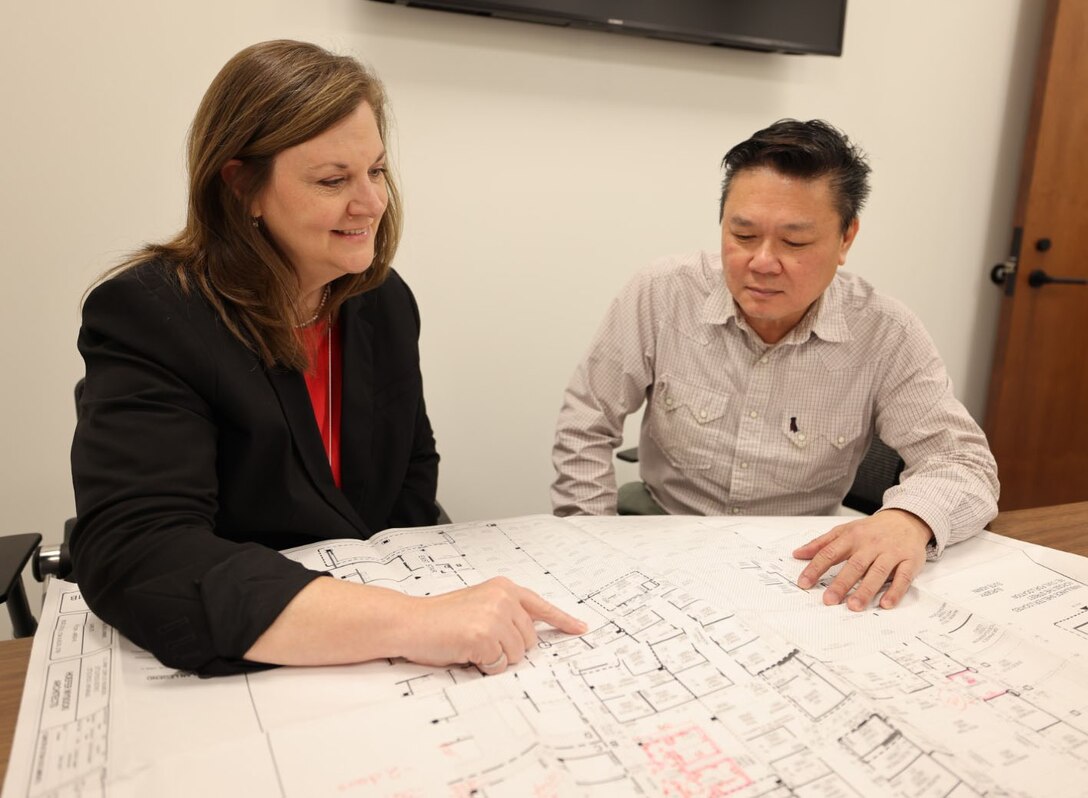 Picture of a woman and man looking at some blueprints.