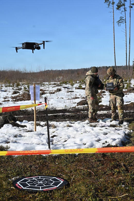 U.S. Army Staff Sgt. Thaisen Nguyen, an infantryman with the Pennsylvania Army National Guard’s 166th Regiment (Regional Training Institute), flies a drone as a Lithuanian grader looks on during the drone event of the Lithuania Land Forces Best Infantry Squad Competition in Rukla, Lithuania, March 5, 2026. Pennsylvania Army Guard Soldiers placed second among foreign teams during the multinational competition. The Pennsylvania National Guard and Lithuania have been partners in the Department of Defense National Guard State Partnership Program since 1993, conducting training and exchanges that strengthen military cooperation and interoperability between the two elements. (U.S. Army National Guard photo by Sgt. 1st Class Tessa Whittlesey)