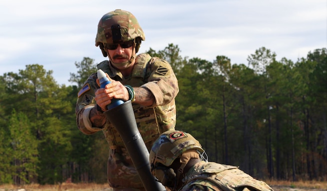 U.S. Army Spc. Nicolas White, an indirect fire infantryman assigned to the Georgia Army National Guard’s Cumming-based Headquarters and Headquarters Company, 3rd Battalion, 121st Infantry Regiment, 48th Infantry Brigade Combat Team, hangs a M879 full range practice cartridge in a M252 81 mm mortar system during a training fire mission, Dec. 15, 2020, at Fort Benning, Georgia. (U.S. Army National Guard photo by Capt. Bryant Wine)