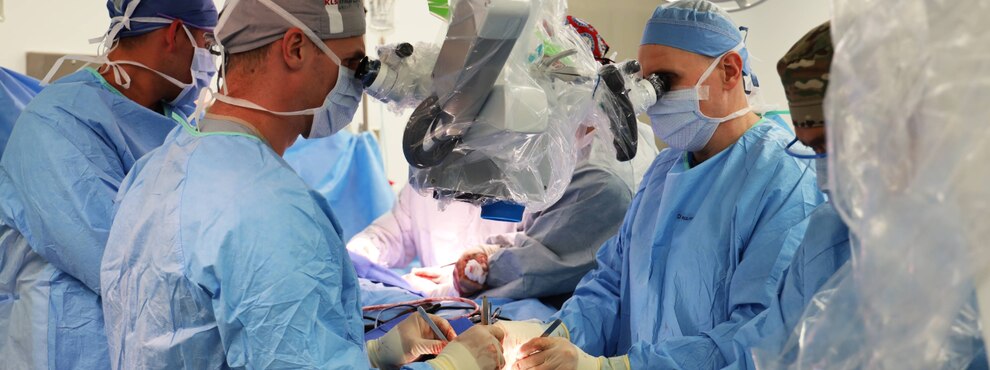 Surgeons using an operating microscope to perform microvascular surgery during a jaw reconstruction.
