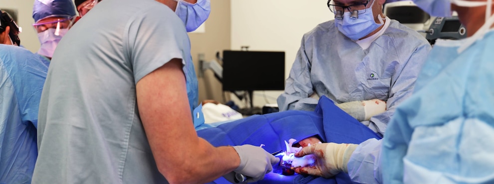 A surgeon positions a 3D-printed surgical guide and secure implants onto a newly reconstructed jaw during a jaw-in-a-day procedure.