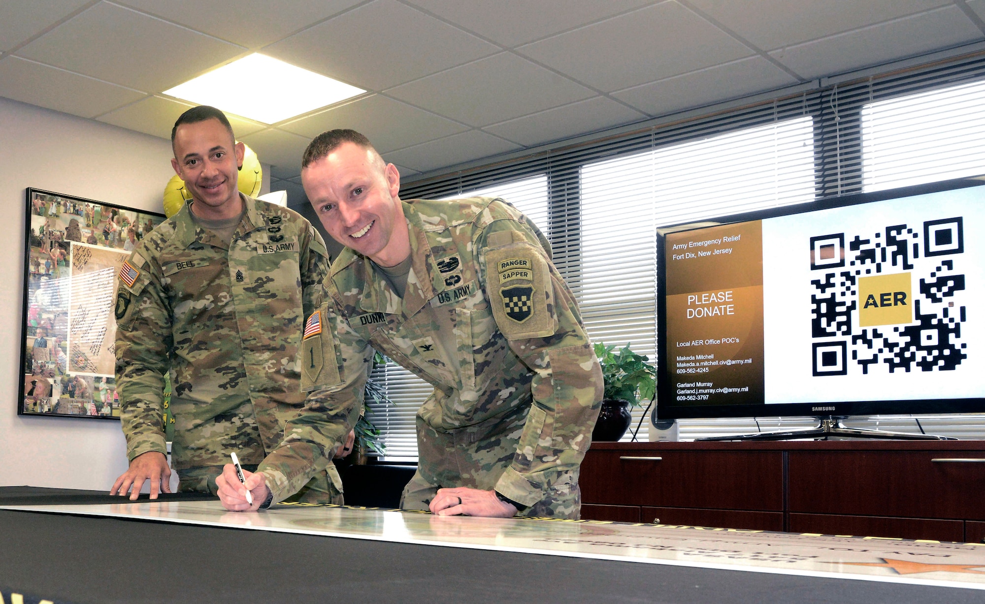 U.S. Army Col. Bryan Dunker (right), Joint Base McGuire-Dix-Lakehurst deputy commander and U.S. Army Support Activity Fort Dix commander, with Command Sgt. Maj. Stonnie Bell Jr., USASA Fort Dix command sergeant major, signs a ceremonial check during the Army Emergency Relief campaign kick-off ceremony at JB MDL, N.J., March 5, 2026. Founded in 1942, AER is the Army’s official nonprofit organization which provides financial assistance to Soldiers and their families during financial hardship through donations. (U.S. Air Force photo by Kris Patterson)