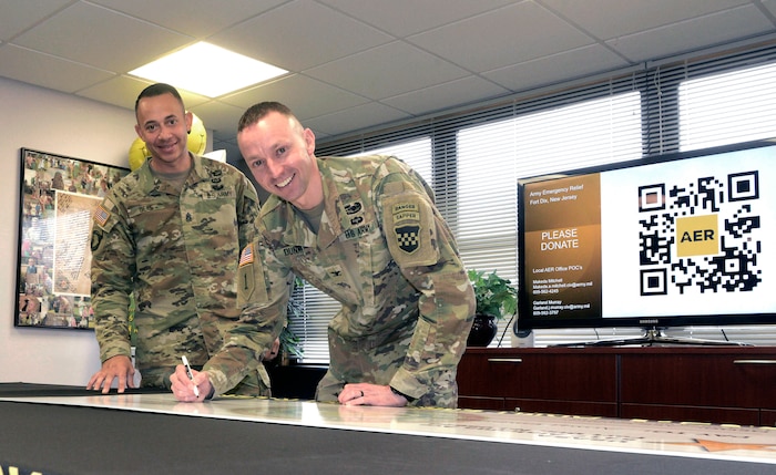 U.S. Army Col. Bryan Dunker (right), Joint Base McGuire-Dix-Lakehurst deputy commander and U.S. Army Support Activity Fort Dix commander, with Command Sgt. Maj. Stonnie Bell Jr., USASA Fort Dix command sergeant major, signs a ceremonial check during the Army Emergency Relief campaign kick-off ceremony at JB MDL, N.J., March 5, 2026. Founded in 1942, AER is the Army’s official nonprofit organization which provides financial assistance to Soldiers and their families during financial hardship through donations. (U.S. Air Force photo by Kris Patterson)