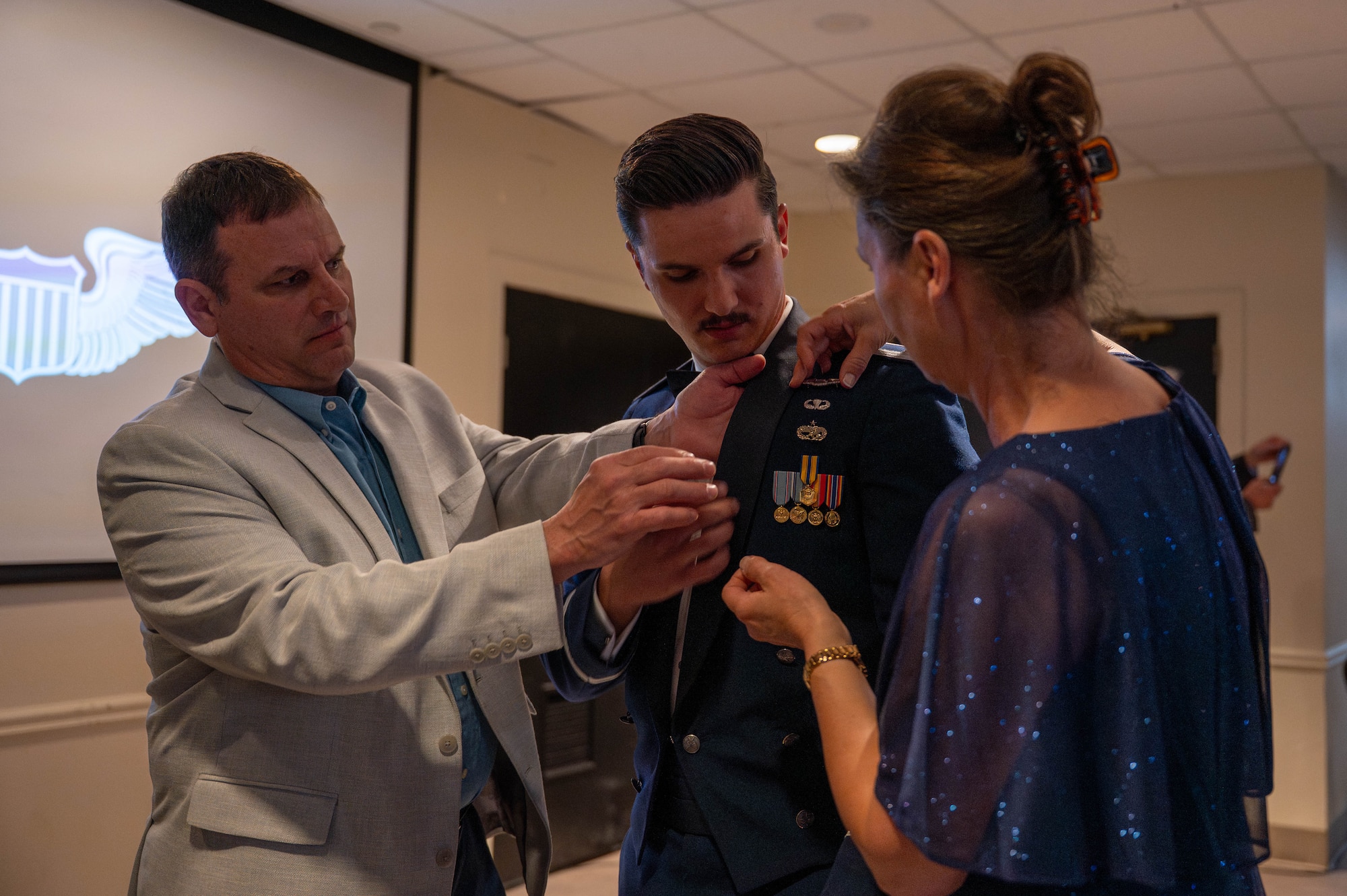 A pilot receives his silver wings with assistance from his guests