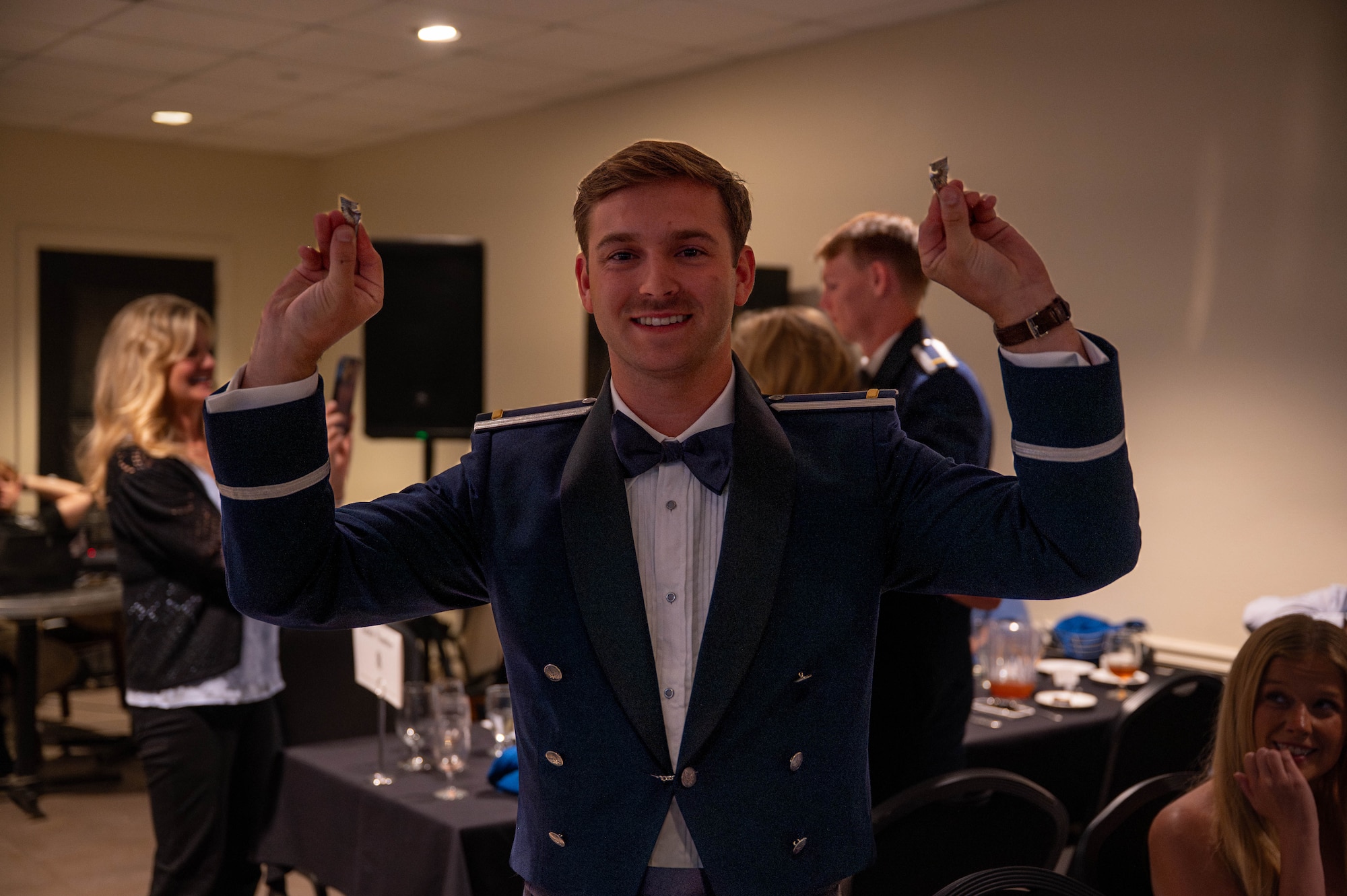 A graduating pilot holds up his broken silver wings.