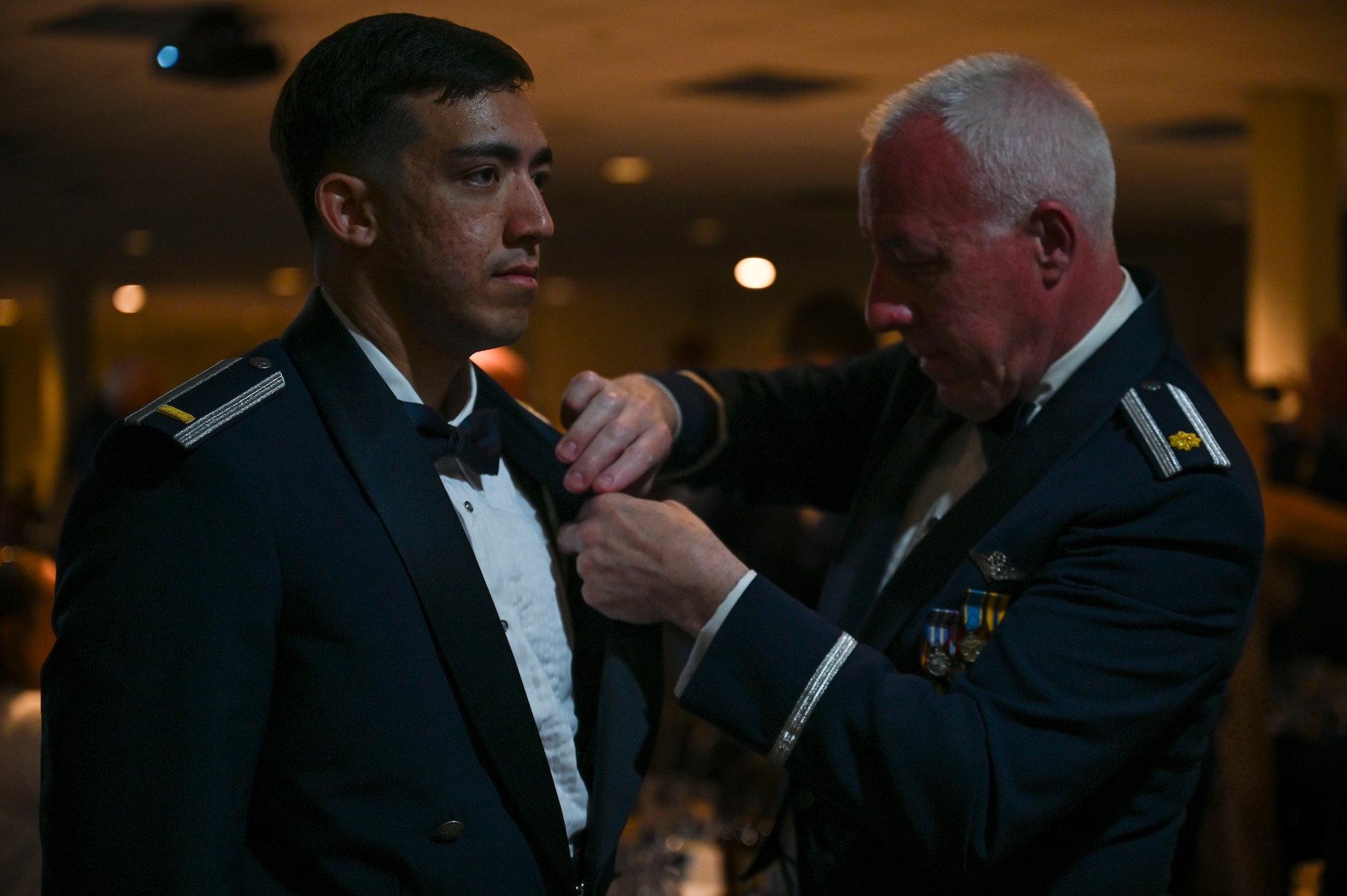 A graduating pilot receives his silver wings with assistance from his guest.