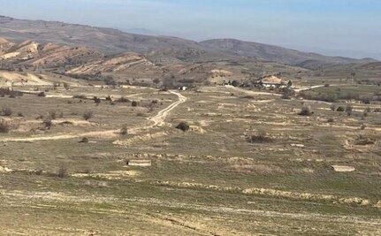A view looking up-range from a hill overlooking a demolition site in North Macedonia, utilized for ordnance disposal with a clear line of sight to the main impact area target. This location is crucial for safely conducting controlled demolitions of explosive hazards. These specialized demolition sites are integral to the training and operational missions of explosive ordnance disposal teams, including those supported by the Vermont Air National Guard's 158th EOD flight.