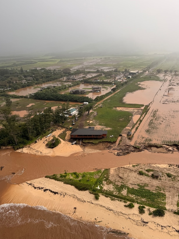 An MH-65 Dolphin helicopter crew assigned to Coast Guard Air Station Barbers Point in Kapolei, Hawaii, flies over a flooded neighborhood in Waialua on the north shore of Oahu March 20, 2026. Coast Guard and Navy aircrews rescued seven people and one dog during flash floods on Oahu Friday. (U.S. Coast Guard photo, courtesy Air Station Barbers Point)