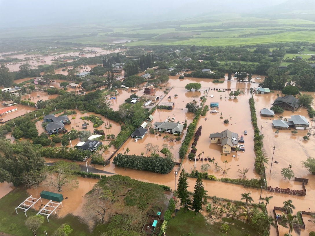 An MH-65 Dolphin helicopter crew assigned to Coast Guard Air Station Barbers Point in Kapolei, Hawaii, flies over a flooded neighborhood in Waialua on the north shore of Oahu March 20, 2026. The Honolulu Department of Emergency Management issued mandatory evacuations for communities in Waialua and Haleiwa following heavy rainfall and flooding across Oahu. (U.S. Coast Guard photo, courtesy Air Station Barbers Point)