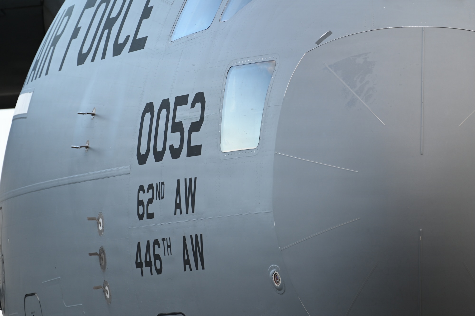 A close up of a U.S. Air Force cargo plane showing the text "62nd Airlift Wing" and "446th Airflift Wing" on the front right side of the aircraft