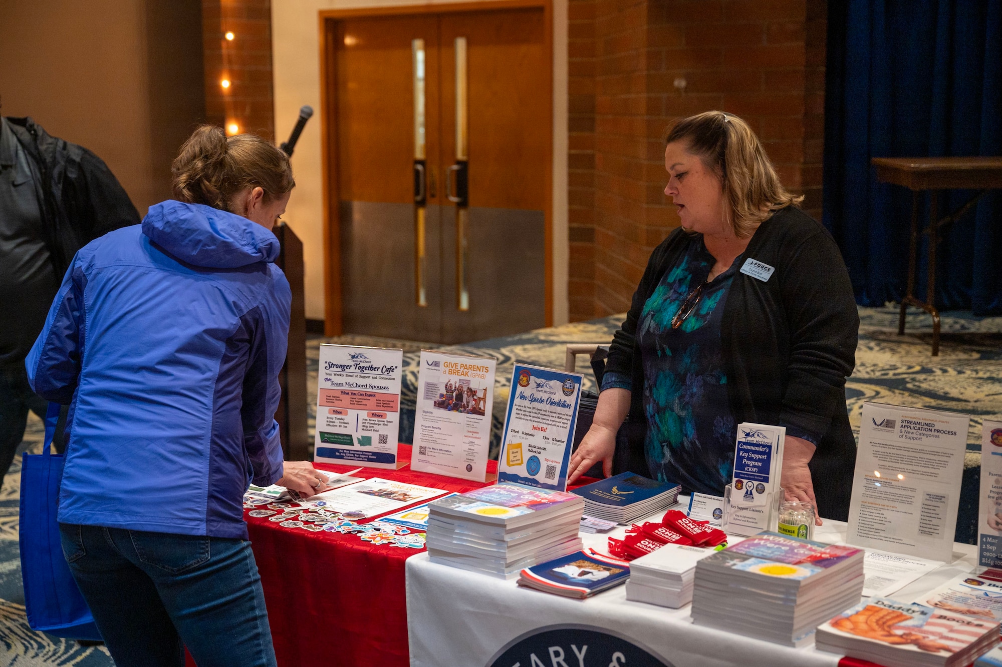 A woman speaks to another woman at a standing booth