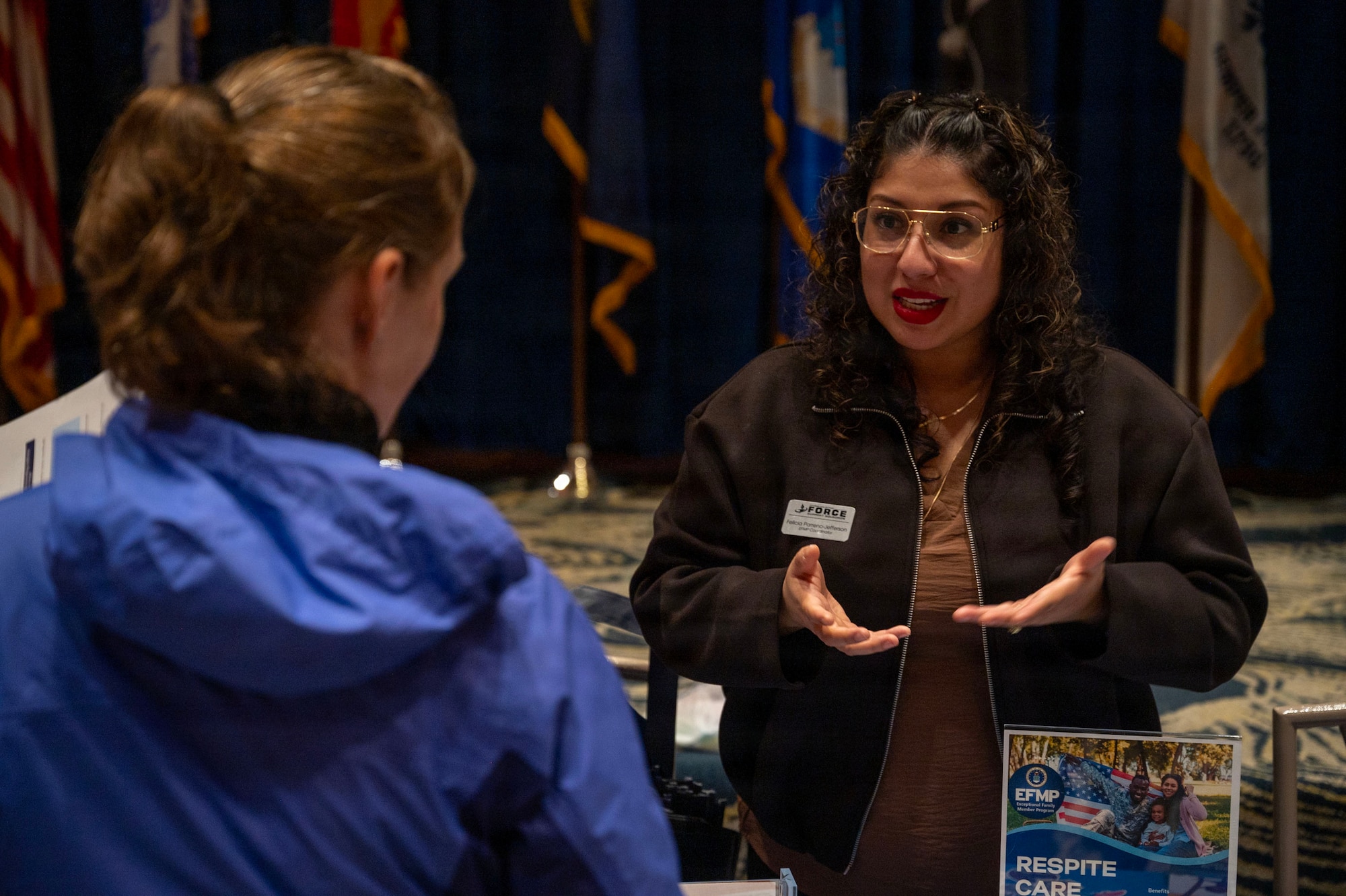 A woman speaks to another woman behind a booth