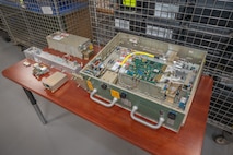 Pieces of a Power Amplifier Module, a piece of military equipment, sit on a table.
