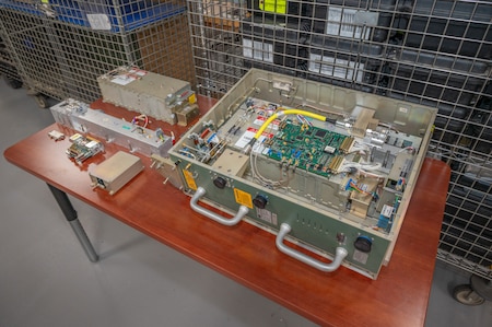 Pieces of a Power Amplifier Module, a piece of military equipment, sit on a table.