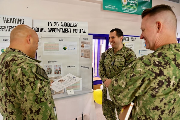 Lt. Christopher Barajas (center) shares his audiology process improvement project with Cmdr. William “Bill” Lawson (right), interim executive officer, and Command Master Chief Richard Moreno (left) during the command process improvement fair at Navy Medicine Readiness and Training Command Twentynine Palms, March 13, 2026. (U.S. Navy photo by Christopher Jones, NMRTC / Naval Hospital Twentynine Palms public affairs officer).