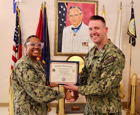 Hospital Corpsman 1st Class Meosha Williams (left) receives a third-place award from Cmdr. William “Bill” Lawson (right), interim executive officer, during the command process improvement fair at Navy Medicine Readiness and Training Command Twentynine Palms, March 13, 2026. Williams led the Revolutionizing Blood Product Release: A Laboratory’s Journey to Efficiency project, which improved patient safety and reduced blood product release times. (U.S. Navy photo by Christopher Jones, NMRTC / Naval Hospital Twentynine Palms public affairs officer).