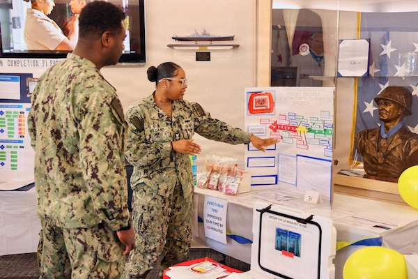 Hospital Corpsman 1st Class Meosha Williams (right) presents her process improvement project to Lt. Cmdr. Kino Anderson (left) during the command process improvement fair at Navy Medicine Readiness and Training Command Twentynine Palms, March 13, 2026. (U.S. Navy photo by Christopher Jones, NMRTC / Naval Hospital Twentynine Palms public affairs officer).