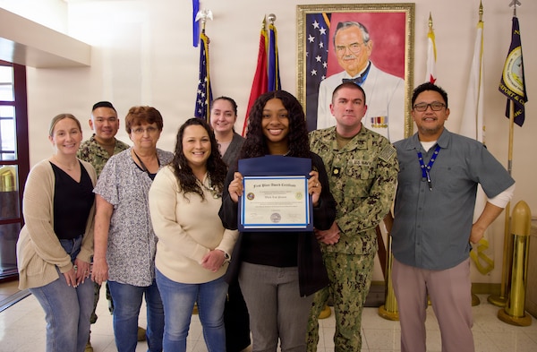 Referral coordinator Jazlyn Antoinette Tharp (center), first-place winner of the command process improvement fair, poses with members of the Directorate for Healthcare Business team at Navy Medicine Readiness and Training Command Twentynine Palms, March 13, 2026. Tharp led the Clear and Legible Reports (CLR) Worklist Project, which improved referral completion rates and streamlined workflow processes. (U.S. Navy photo by Christopher Jones, NMRTC / Naval Hospital Twentynine Palms public affairs officer).