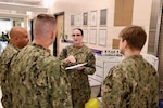 Sailors share their process improvement projects with Cmdr. William “Bill” Lawson, interim executive officer, and Command Master Chief Richard Moreno during the command process improvement fair at Navy Medicine Readiness and Training Command Twentynine Palms, March 13, 2026. (U.S. Navy photo by Christopher Jones, NMRTC / Naval Hospital Twentynine Palms public affairs officer).