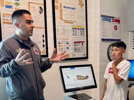 Lt. Joseph Zelasko, a dentist at U.S. Naval Hospital Guantanamo Bay, speaks with students from W.T. Sampson Elementary and High School about oral health, including dental exams, cavities and preventive care, during a field trip March 10, 2026. Student Steven Gomez listens as Zelasko explains how routine dental care supports overall health and readiness. The visit was part of an educational outreach initiative by U.S. Navy Medicine Readiness and Training Command Guantanamo Bay to introduce students to careers in military medicine. (U.S. Navy photo by Emily McCamy)