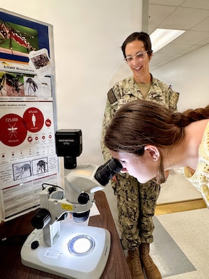 Lexi McCamy, a student from W.T. Sampson Elementary and High School, looks at a mosquito through a microscope as Lt. Jyl Bean, an environmental health officer at U.S. Naval Hospital Guantanamo Bay, explains how mosquitos are identified, March 10, 2026. The hands-on activity introduced students to preventive medicine and the role of environmental health in disease transmission and prevention. The visit was part of an educational outreach initiative by U.S. Navy Medicine Readiness and Training Command Guantanamo Bay to introduce students to careers in military medicine. (U.S. Navy photo by Emily McCamy)